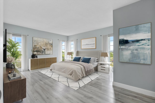 bedroom with multiple windows and light hardwood / wood-style flooring