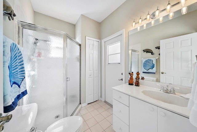 bathroom featuring tile patterned flooring, vanity, toilet, and a shower with shower door