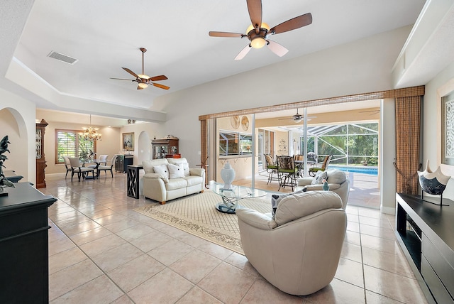 tiled living room with ceiling fan with notable chandelier