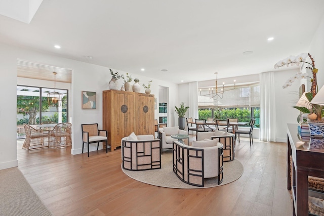 living room featuring a wealth of natural light, light hardwood / wood-style flooring, and a notable chandelier