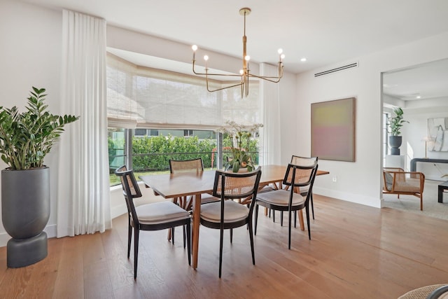 dining area with hardwood / wood-style flooring and an inviting chandelier