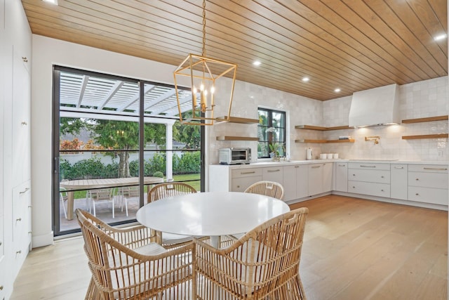 dining room featuring an inviting chandelier, light hardwood / wood-style flooring, and wooden ceiling