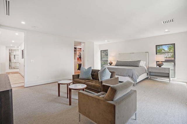 bedroom featuring light carpet, a walk in closet, a closet, and ensuite bathroom