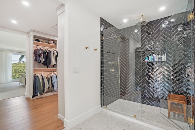 bathroom with wood-type flooring, tile walls, and tiled shower