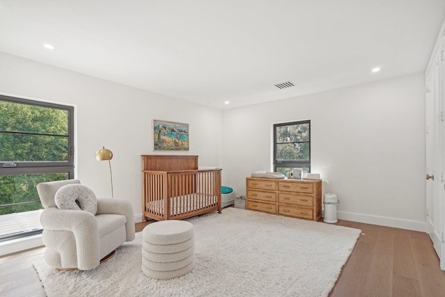 bedroom featuring hardwood / wood-style flooring, multiple windows, and a nursery area