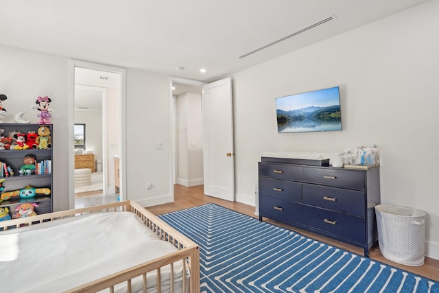 bedroom featuring connected bathroom and hardwood / wood-style flooring