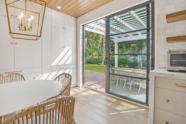 dining room featuring a chandelier, light hardwood / wood-style floors, and wooden ceiling