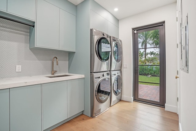 laundry area featuring cabinets, sink, stacked washer / dryer, and light wood-type flooring