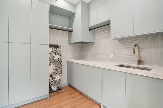 kitchen featuring sink, white cabinetry, light hardwood / wood-style flooring, and decorative backsplash