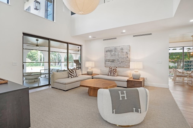 living room with light hardwood / wood-style floors, a high ceiling, and plenty of natural light