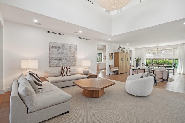 living room featuring an inviting chandelier, a high ceiling, and light hardwood / wood-style floors