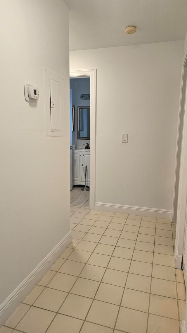 hall with light tile patterned flooring, sink, and electric panel