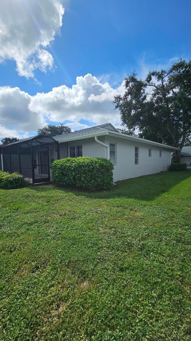 view of side of property with a sunroom and a yard