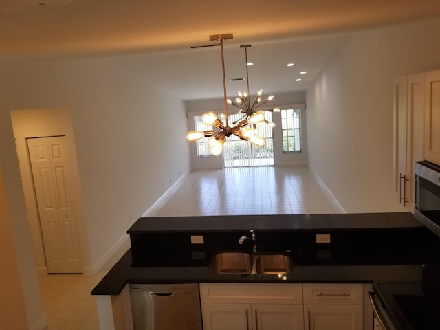 kitchen featuring stove, sink, a notable chandelier, white cabinetry, and decorative light fixtures