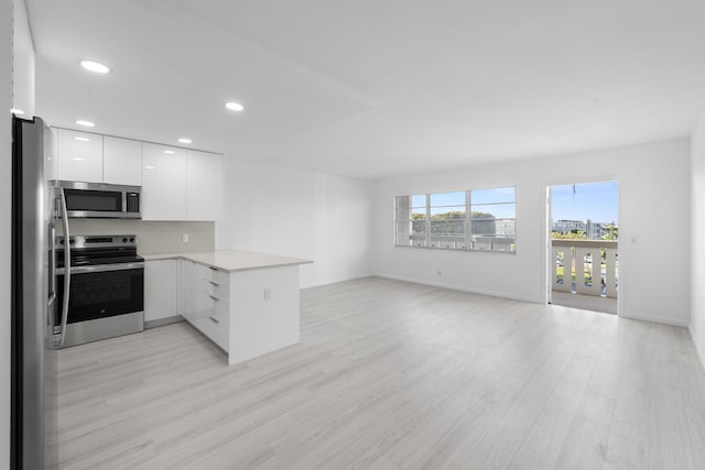 kitchen with stainless steel appliances, white cabinetry, light hardwood / wood-style floors, and kitchen peninsula