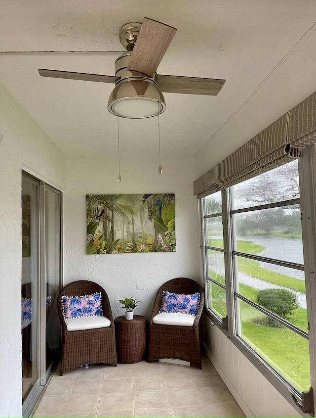 sunroom / solarium with a water view and ceiling fan