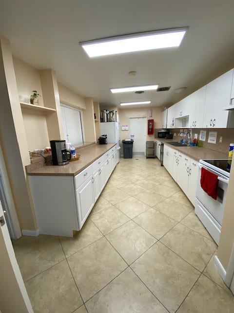 kitchen with white cabinets, sink, white electric stove, decorative backsplash, and light tile patterned floors