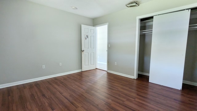 unfurnished bedroom with a closet and dark wood-type flooring