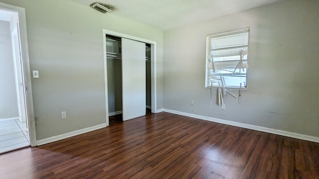 unfurnished bedroom featuring a closet and dark hardwood / wood-style floors