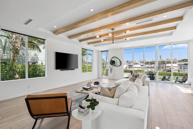 living room featuring light wood-type flooring, a notable chandelier, beamed ceiling, and plenty of natural light