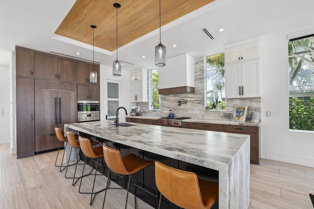 kitchen with appliances with stainless steel finishes, white cabinets, a kitchen island with sink, and sink