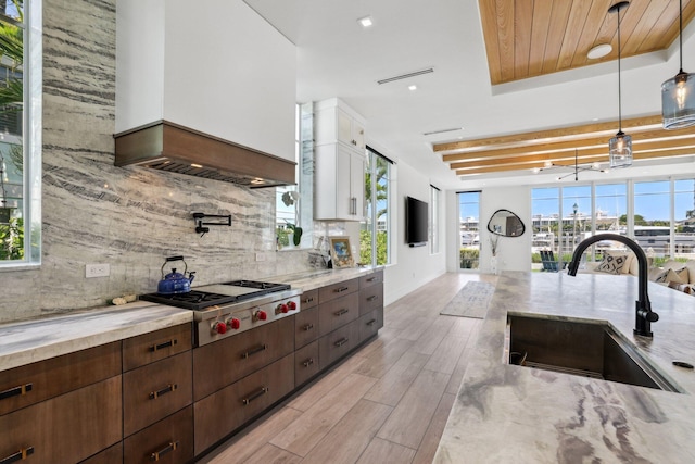 kitchen featuring sink, pendant lighting, white cabinets, decorative backsplash, and light hardwood / wood-style flooring