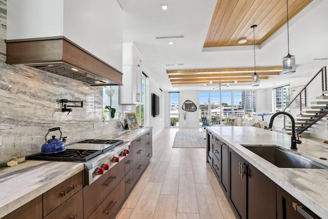 kitchen featuring backsplash, sink, pendant lighting, custom exhaust hood, and white cabinetry