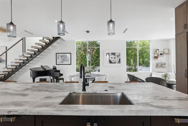 kitchen featuring decorative light fixtures, dark brown cabinetry, sink, and floor to ceiling windows