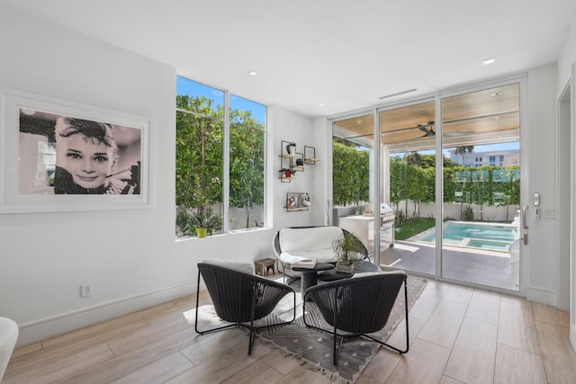 living area with a wealth of natural light, light hardwood / wood-style floors, and floor to ceiling windows