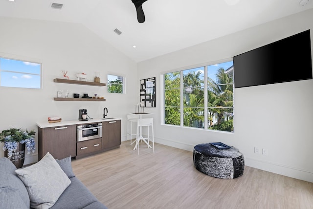 living room with lofted ceiling, light wood-type flooring, a healthy amount of sunlight, and ceiling fan