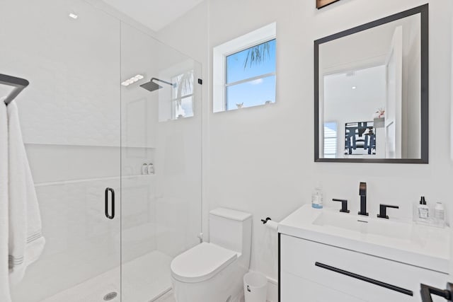 bathroom with toilet, vanity, and a shower with door