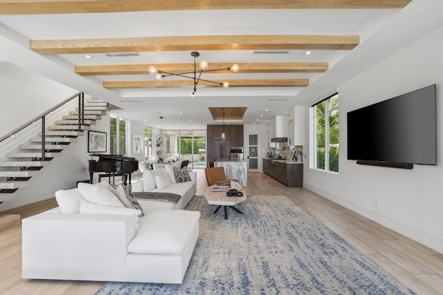 living room featuring beam ceiling, a notable chandelier, light hardwood / wood-style floors, and plenty of natural light