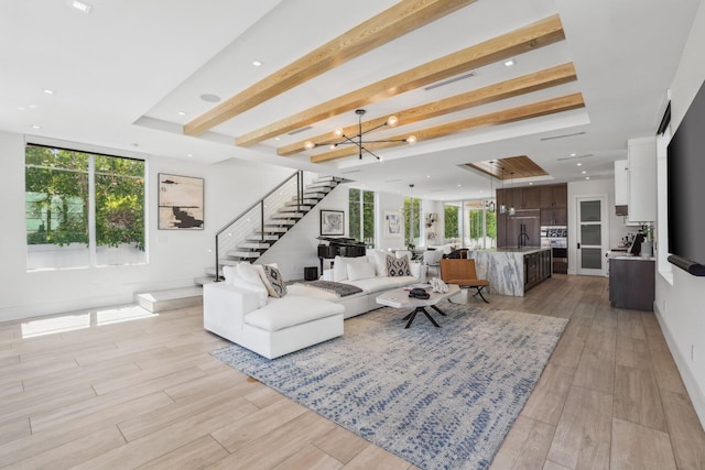 living room with beam ceiling, light hardwood / wood-style flooring, sink, an inviting chandelier, and a raised ceiling