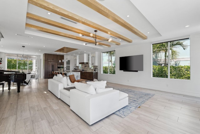 living room with beam ceiling, an inviting chandelier, and light wood-type flooring