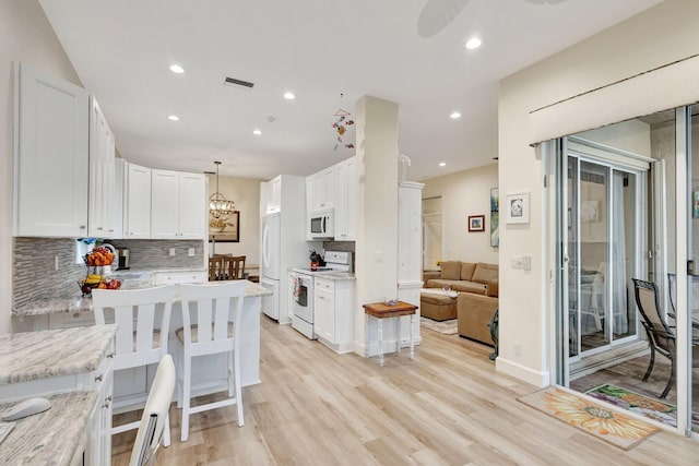 kitchen with white cabinetry, light stone counters, white appliances, and light hardwood / wood-style flooring