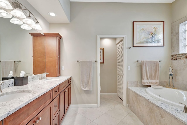 bathroom with tile patterned flooring, vanity, and tiled tub