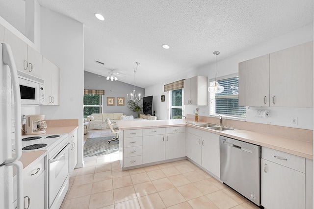 kitchen featuring kitchen peninsula, vaulted ceiling, pendant lighting, sink, and white appliances