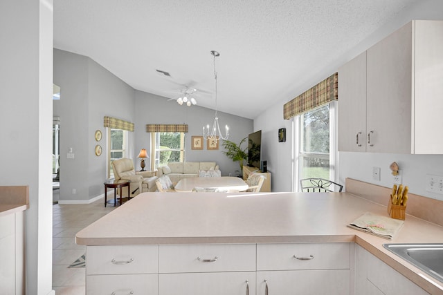 kitchen featuring lofted ceiling, a healthy amount of sunlight, light tile patterned flooring, and kitchen peninsula