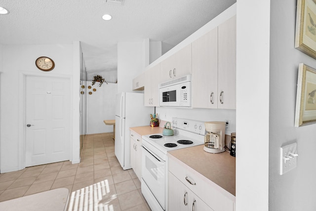 kitchen with white cabinets, a textured ceiling, light tile patterned floors, and white appliances