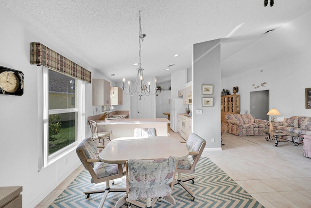 dining area with sink, a textured ceiling, vaulted ceiling, light tile patterned floors, and a chandelier