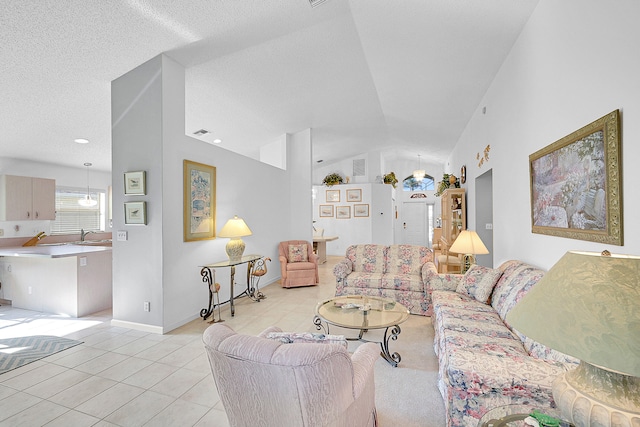 tiled living room with sink, a textured ceiling, and high vaulted ceiling