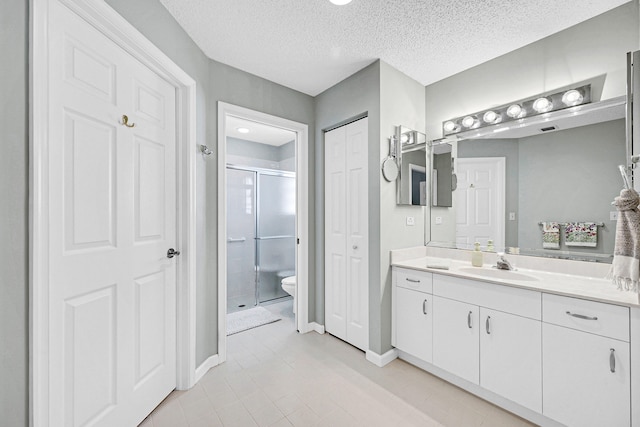 bathroom featuring vanity, a shower with shower door, a textured ceiling, and toilet