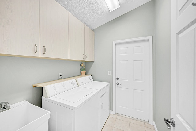 laundry room with cabinets, light tile patterned floors, a textured ceiling, washing machine and clothes dryer, and sink