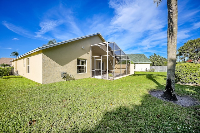 rear view of house with a yard, a patio, and glass enclosure