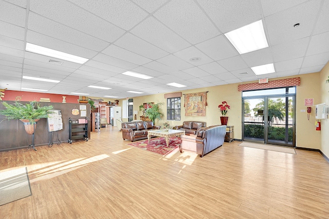 living room with a drop ceiling and light hardwood / wood-style flooring