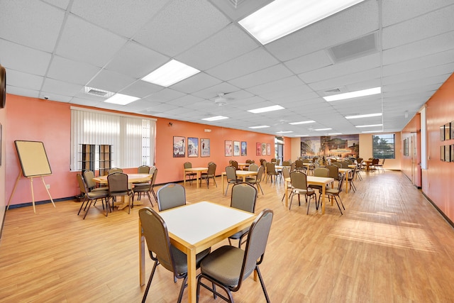 dining room with a drop ceiling and light wood-type flooring