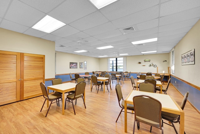 dining area featuring a drop ceiling and light hardwood / wood-style flooring