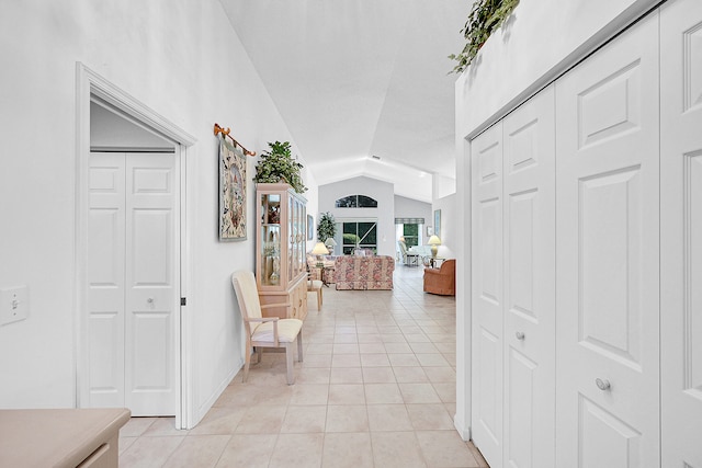 hall with lofted ceiling and light tile patterned floors