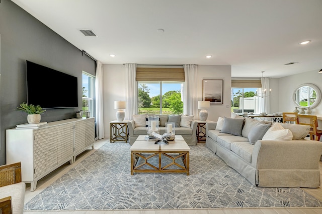 living room with hardwood / wood-style flooring, an inviting chandelier, and plenty of natural light