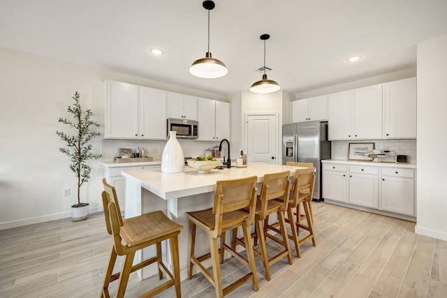 kitchen with white cabinetry, pendant lighting, appliances with stainless steel finishes, and light wood-type flooring